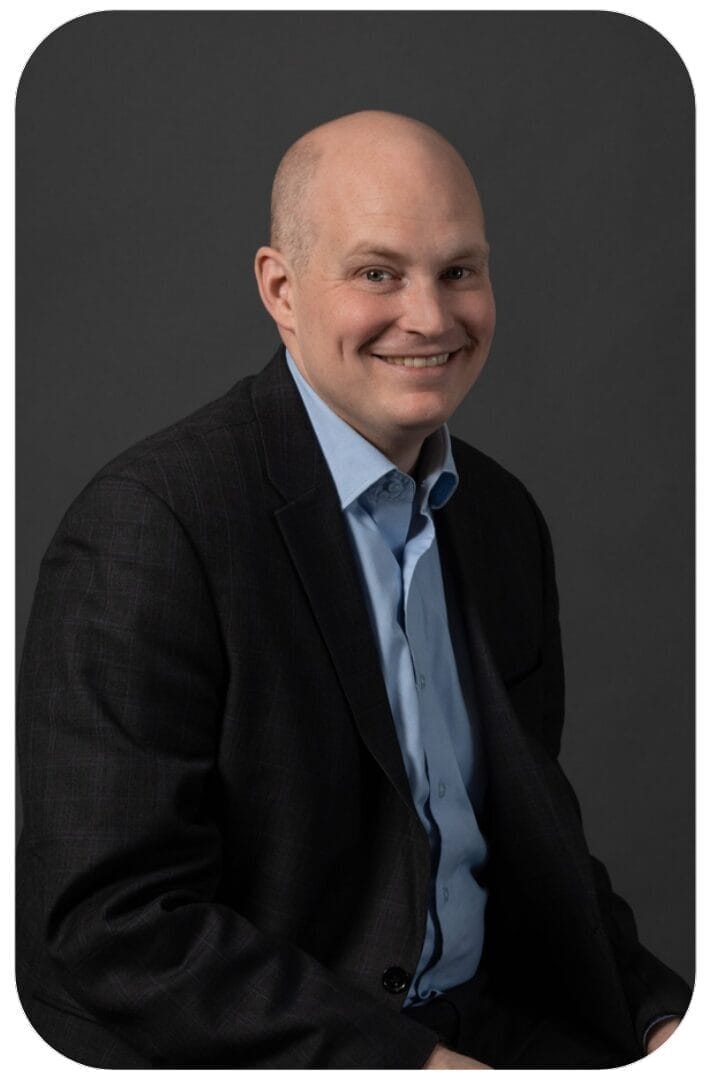 Smiling bald man in blazer against gray background